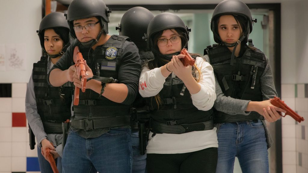 A group of students are wearing helmets, orange guns, and vests.