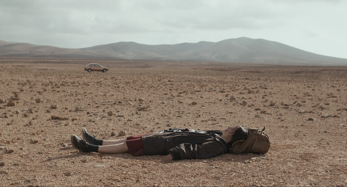 Woman lays on an empty desert landscape.