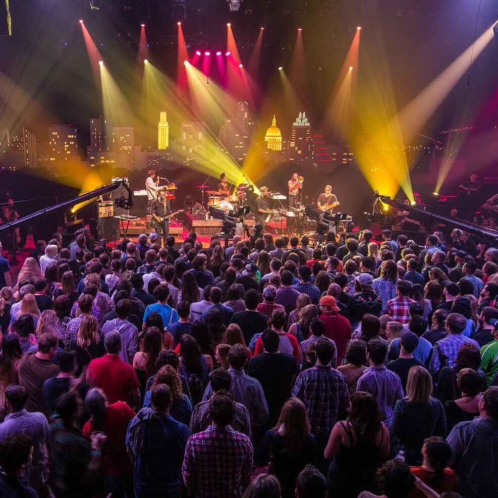 stage with bright color lights and a crowd of people in the foreground